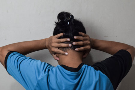Back view of person covering their ears above the head on beige background