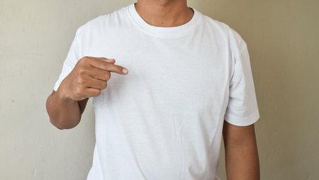Man pointing index finger a copy space on his blank white t-shirt