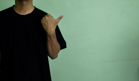 Young man looking and pointing finger to the side to an empty mock-up spaceの写真素材