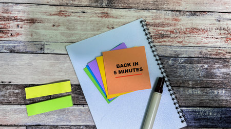 Concept of Back in 5 Minutes write on sticky notes isolated on Wooden Table.