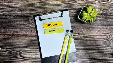 Concept of Inclusive Hiring write on sticky notes isolated on Wooden Table.の写真素材