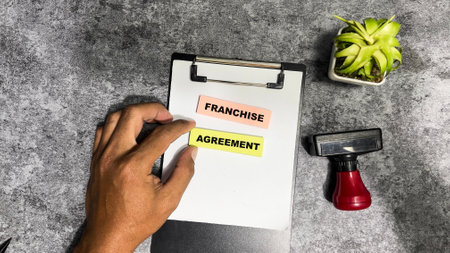 Concept of Franchise Agreement write on sticky notes isolated on Wooden Table.