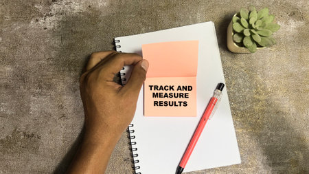 Concept of Track and Measure Results write on sticky notes isolated on Wooden Table.