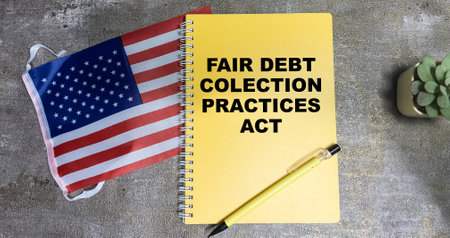 Concept of Fair Debt Collection Practices Act write on book and Flag of the United States isolated on Wooden Table.の写真素材