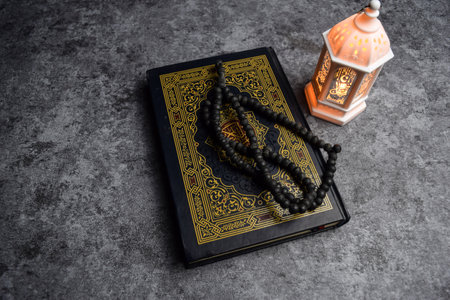 The holy quran, prayer beads, golden ramadhan lamp with islamic rosary beads on dark background ramadhan. Islamic conceptの写真素材
