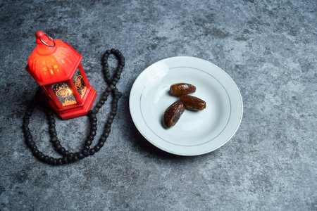 Dates, prayer beads, golden ramadhan lamp with islamic rosary beads on dark background ramadhan.の写真素材