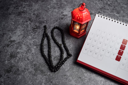 Calendar, prayer beads, golden ramadhan lamp with islamic rosary beads on dark background ramadhan.の写真素材