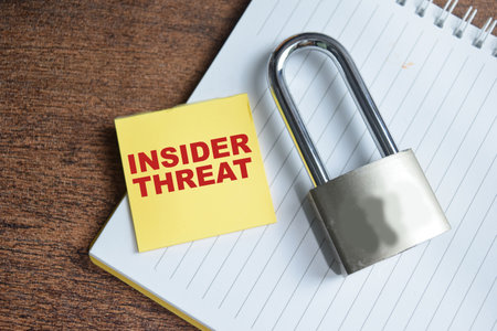 Concept of Insider Threat write on sticky notes and padlock isolated on Wooden Table.の写真素材