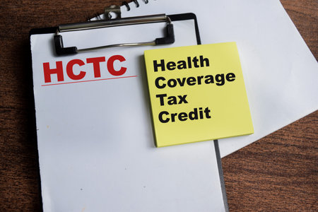 Concept of HCTC - Health Coverage Tax Credit write on sticky notes isolated on Wooden Table.