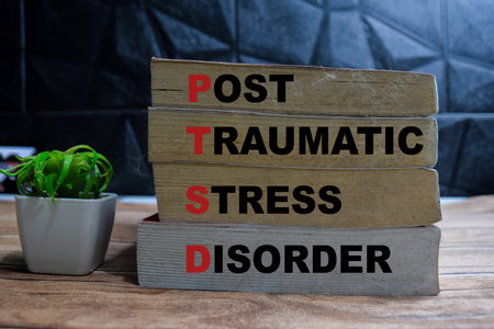 Books with words PTSD - Post Traumatic Stress Disorder on wooden table and black backgroundの写真素材