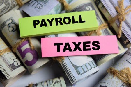 Concept Payroll Taxes on sticky notes on a wooden table with dollar billsの写真素材