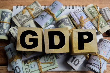 Concept word GDP on wooden blocks on a wooden table with dollar billsの写真素材