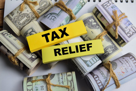 Concept Tax Relief on sticky notes on a wooden table with dollar billsの写真素材