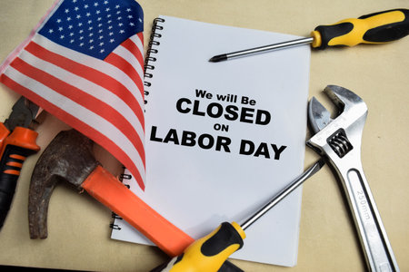 Concept of We Will be Closed on Labor Day write on book with and tools and the flag the united states isolated on Wooden Table.の写真素材