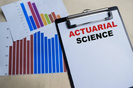 Concept of Actuarial science write on clipboard isolated on Wooden Table.の写真素材