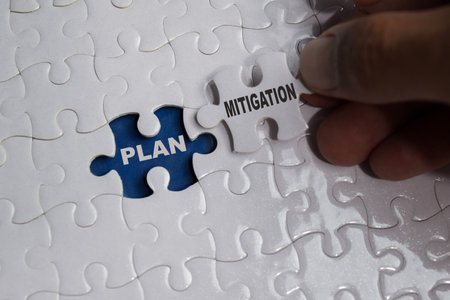 Hand holding piece of jigsaw puzzle with word Mitigation plan. Business and finance concept