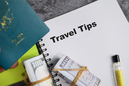 Concept of Travel tips write on book isolated on Wooden Table. with passport, dollar billsの写真素材