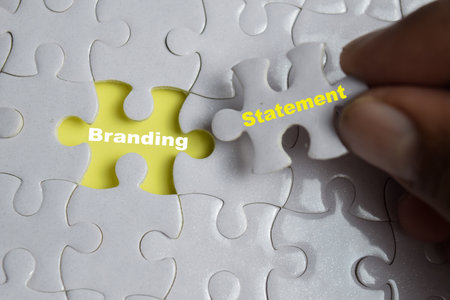 Hand holding piece of jigsaw puzzle with word Branding statement. Business and finance conceptの写真素材