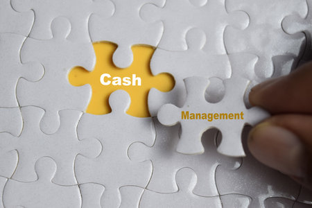 Hand holding piece of jigsaw puzzle with word Cash management. Business and finance concept