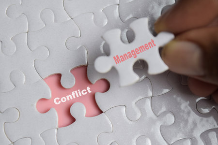 Hand holding piece of jigsaw puzzle with word Conflict management. Business and finance concept