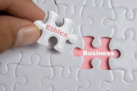 Hand holding piece of jigsaw puzzle with word Business Ethics. Business and finance conceptの写真素材