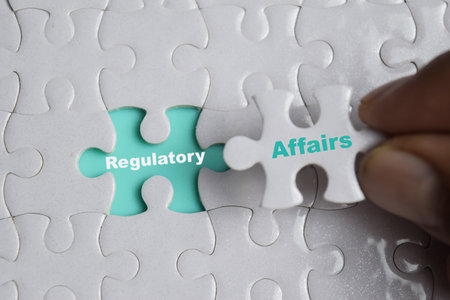 Hand holding piece of jigsaw puzzle with word Regulatory affairs. Business and finance concept