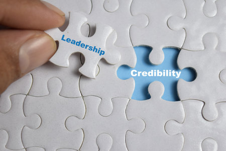 Hand holding piece of jigsaw puzzle with word Credibility and leadership. Business and finance conceptの写真素材