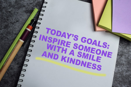 Concept of today's goals - inspire someone with a smile and kindness write on book isolated on Wooden Table.の写真素材