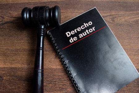Concept of copyright law in spanish write on book with gavel isolated on Wooden Table.