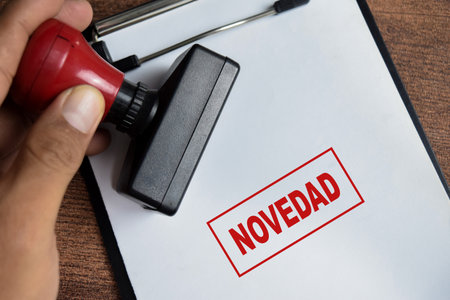 Red Handle Rubber Stamper and Novelty in spanish text above clipboard isolated on wooden background....