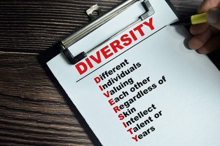 Concept of DIVERSITY - Different, Individuals, Valuing, Each other, Regardless of, skin, Intellect, Talent or, Years write on clipboard isolated on Wooden Table.の写真素材