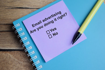 Email advertising are you doing it right write on sticky notes isolated on Wooden Table. A person is...