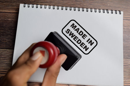 Red Handle Rubber Stamper and Made in Sweden text above book isolated on wooden background