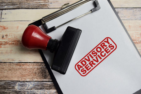 Red Handle Rubber Stamper and Advisory services text above clipboard isolated on wooden backgroundの写真素材