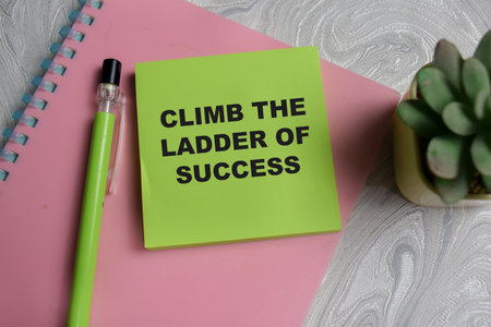 Concept of climb the ladder of success write on sticky notes isolated on Wooden Table.