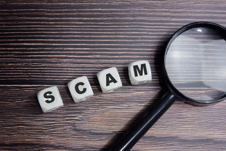 The word Scam on stacked wooden cubes on the table. Business and finance concept