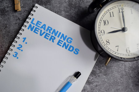 Concept of Learning never ends write on book Supported by an additional services isolated on Wooden Table.の写真素材