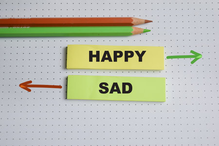 Concept of happy or sad write on sticky notes isolated on Wooden Table.