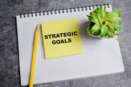 Concept of Strategic goals write on sticky notes isolated on Wooden Table.