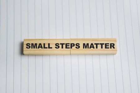 Small steps matter on stacked wooden cubes. Business and finance concept