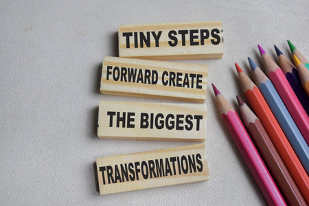 Tiny steps forward create the biggest transformations on stacked wooden cubes on the table.