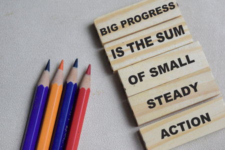 Big progress is the sum of small steady action on stacked wooden cubes on the table.の写真素材