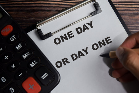 Concept of one day or day one write on clipboard isolated on Wooden Table.の写真素材