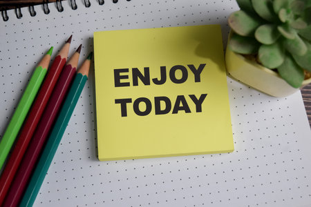 Concept of enjoy today write on sticky notes isolated on Wooden Table.の写真素材