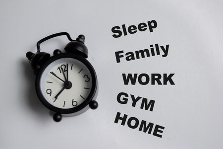 Concept of life balance and planning activities with wall clock write on book with keywords isolated on Wooden Table.の写真素材