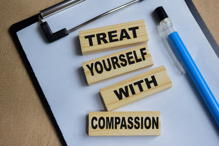 treat yourself with compassion on stacked wooden cubes on the table.の写真素材