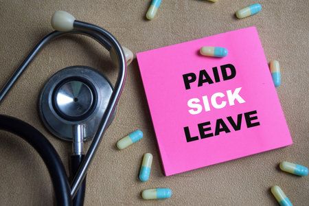 Concept of paid sick leave write on sticky notes isolated on Wooden Table.の写真素材