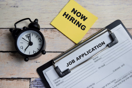 Concept of now hiring and job application write on clipboard isolated on Wooden Table.の写真素材