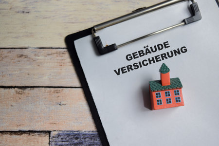 Concept of gebaude versicherung in german it means building insurance write on clipboard isolated on Wooden Table.の写真素材
