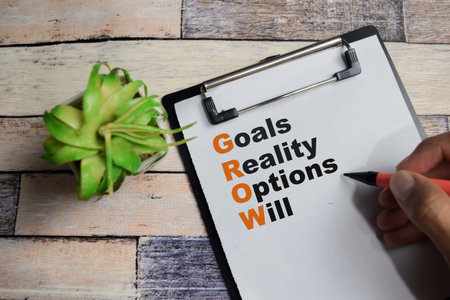 Concept of GROW - Goals, Reality, Options and Will write on clipboard isolated on Wooden Table.の写真素材